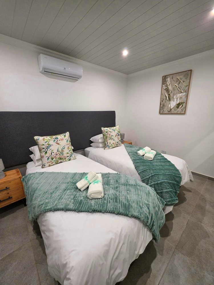 Room 3, two beds with sage green throws and a jute rug